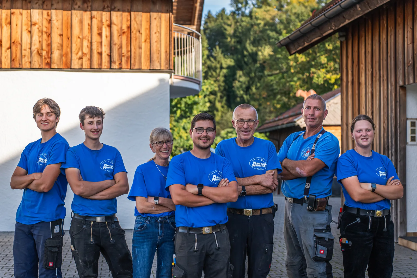 Das Team der Wolfgang Winnefeld GmbH steht lachend mit verschränkten Armen vor dem Betrieb in Rohrdorf